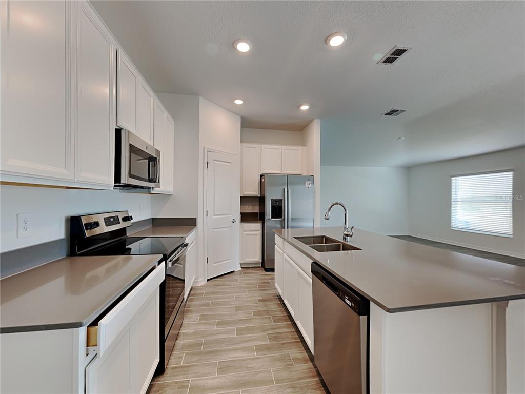 A modern kitchen features white cabinets, stainless steel appliances, and a large central island — 301 PIAVE STREET, HAINES CITY, FL