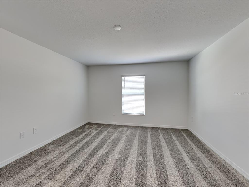 An empty bedroom features white walls, gray carpet, and a single window with blinds — 301 PIAVE STREET, HAINES CITY, FL