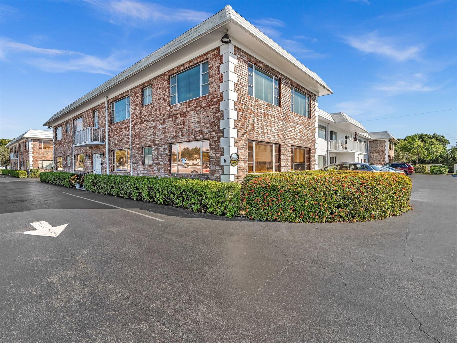 A two-story brick apartment building features a corner entrance, large windows, and manicured landscaping — 330 S Cypress Road # 628, Pompano Beach FL 33060, POMPANO BEACH, FL