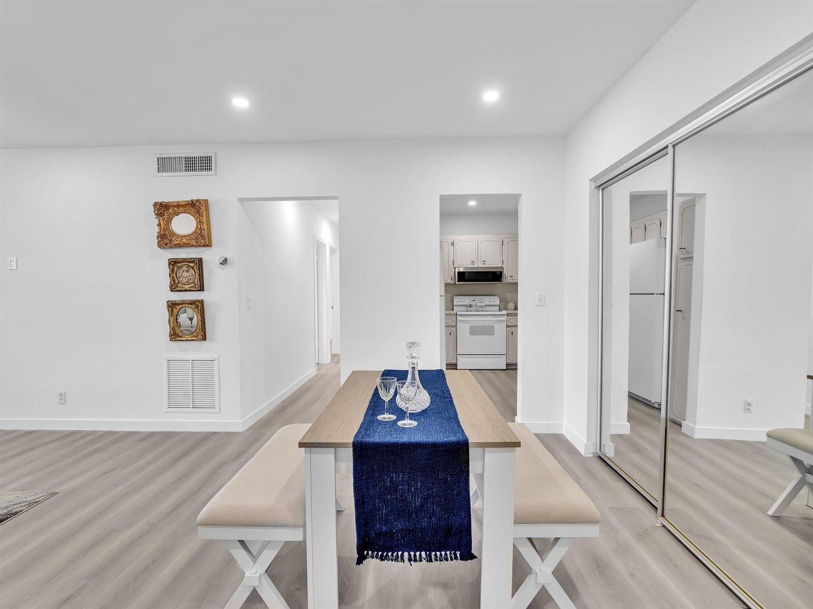 A dining area features a wooden table with benches, a blue runner, and mirrored closet doors — 330 S Cypress Road # 628, Pompano Beach FL 33060, POMPANO BEACH, FL