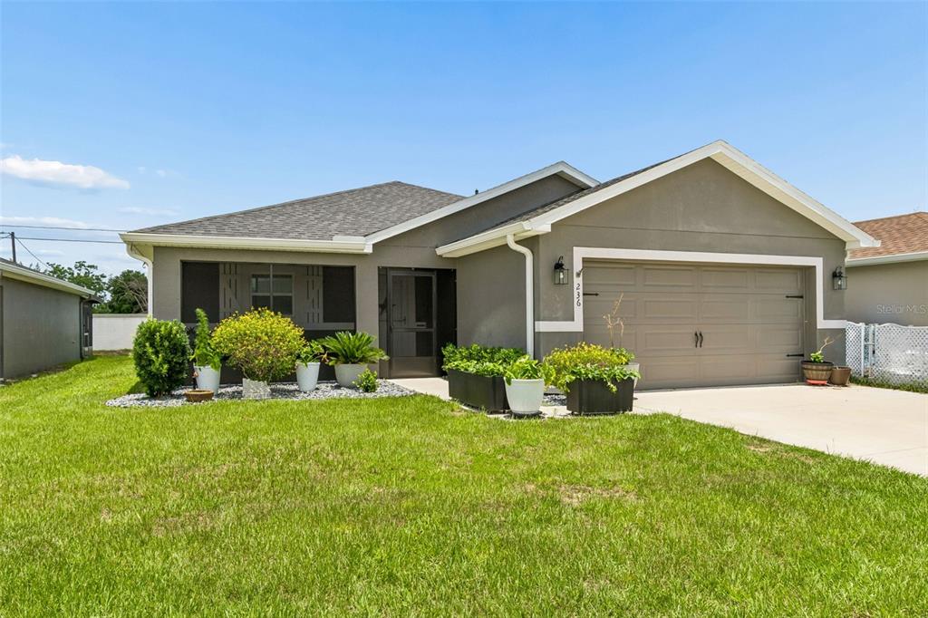 A single-story house with a gray exterior, a two-car garage, and a front lawn — 236 FOXTAIL LOOP, DAVENPORT, FL