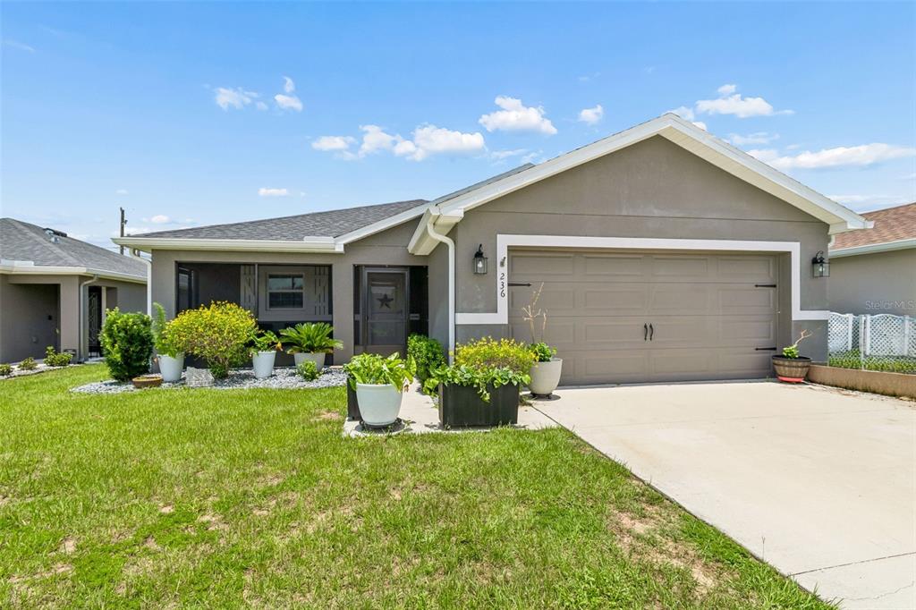 A single-story house with a gray exterior, a two-car garage, and a screened front porch — 236 FOXTAIL LOOP, DAVENPORT, FL