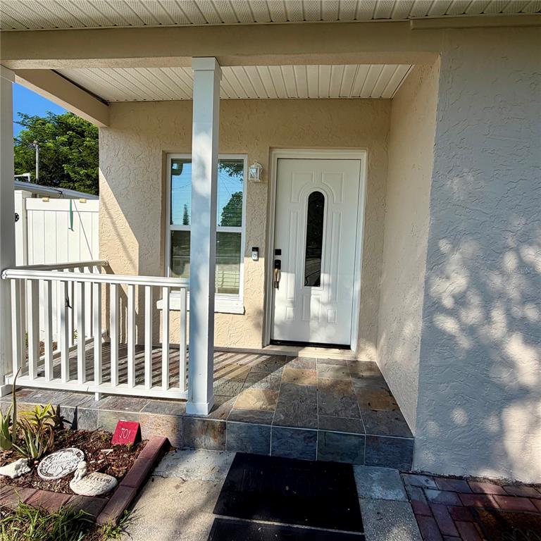 A front porch with a white railing, tiled floor, and a white front door — 706 ROMANO AVENUE, ORLANDO, FL