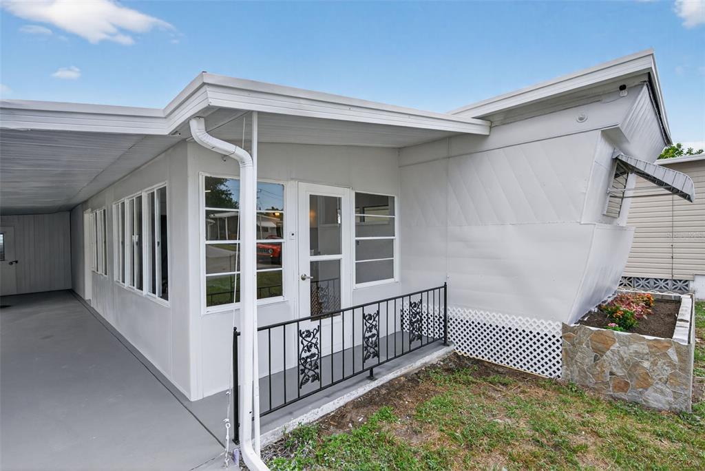 A white mobile home exterior features a covered carport, a small porch, and metal siding — 5162 BOCA RATON AVENUE, SARASOTA, FL