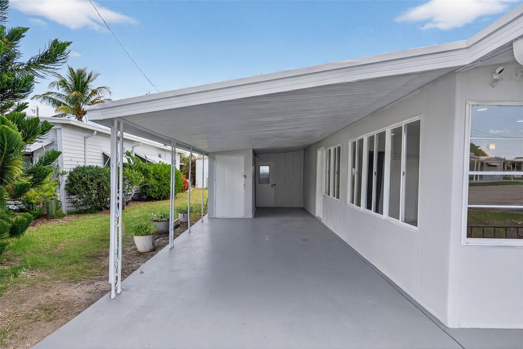 A covered concrete carport extends along the side of a white mobile home — 5162 BOCA RATON AVENUE, SARASOTA, FL