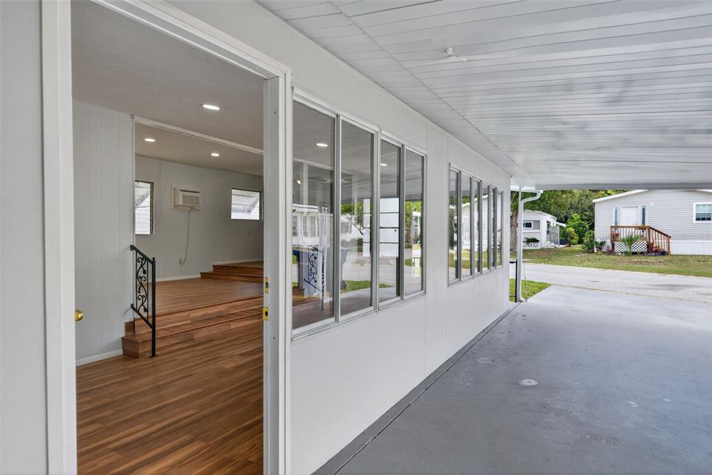 A view from a covered carport looking into a room with wood-look flooring and steps — 5162 BOCA RATON AVENUE, SARASOTA, FL