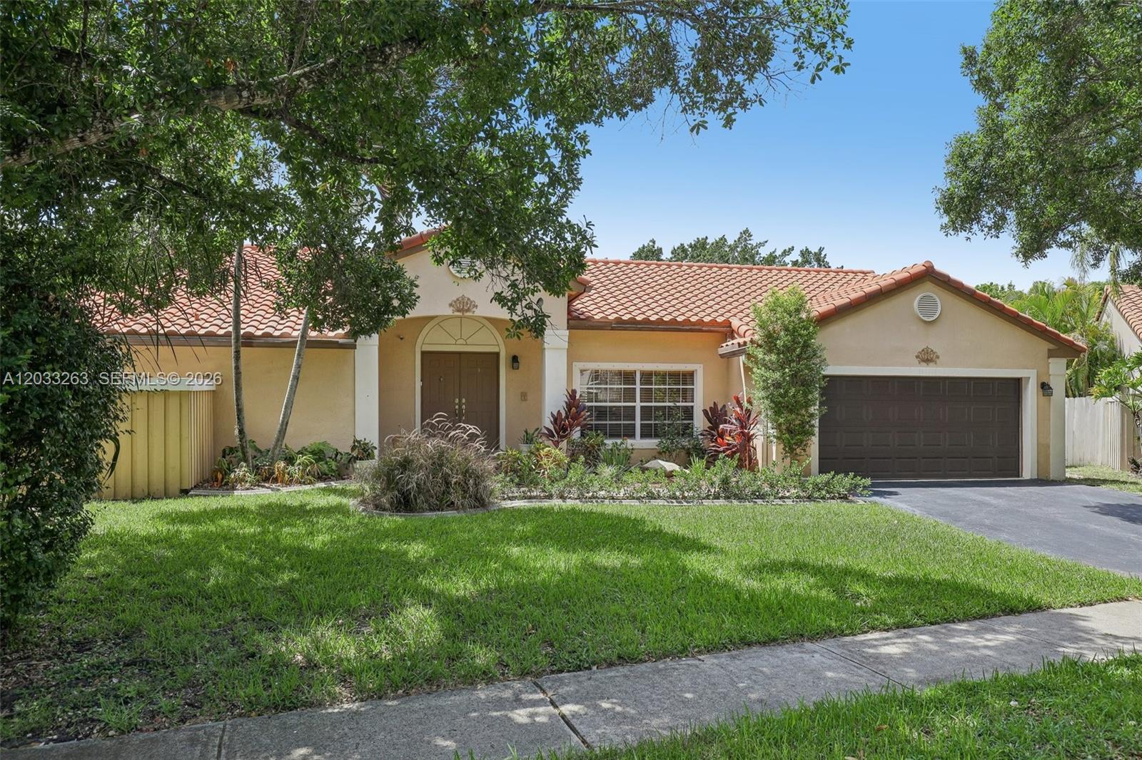 A single-story house with a terracotta tile roof, beige stucco walls, and a brown garage — 13100 NW 11th Dr, Sunrise FL 33323, SUNRISE, FL