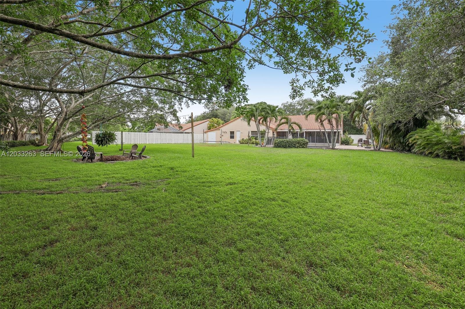 A large, grassy backyard features a fire pit area, mature trees, and a house exterior — 13100 NW 11th Dr, Sunrise FL 33323, SUNRISE, FL