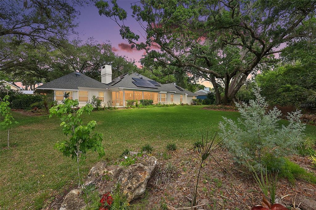 The rear exterior of a single-story house features a screened porch and rooftop solar panels — 33746 SPRING DRIVE, LEESBURG, FL