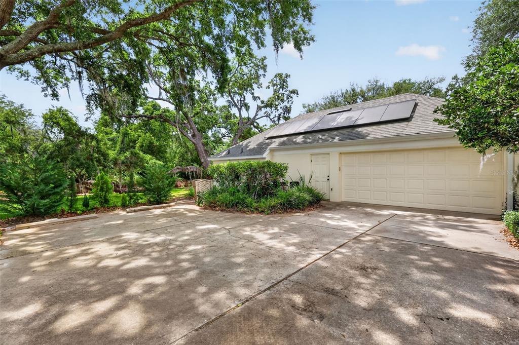 A concrete driveway leads to a garage with solar panels on the roof — 33746 SPRING DRIVE, LEESBURG, FL