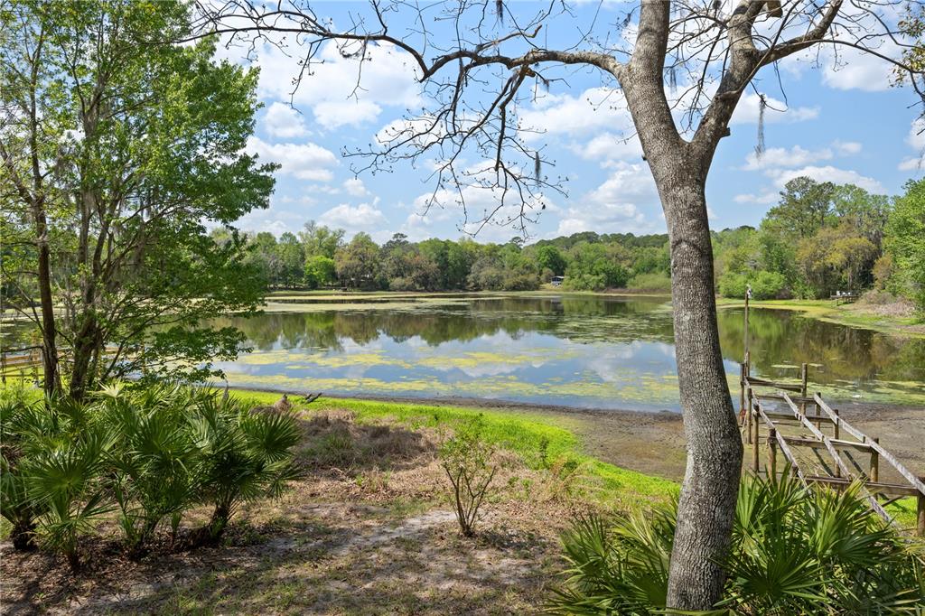 A view of a lake with a wooden dock and surrounding trees under a sky — 2550 SE 31ST STREET, GAINESVILLE, FL