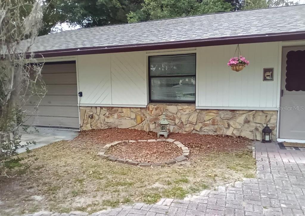 A single-story house exterior features white vertical siding, stone veneer, a garage, and a walkway — 2900 NE 49TH STREET, OCALA, FL