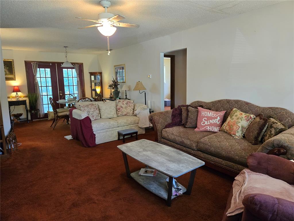 A living room features brown carpeting, two sofas, a coffee table, and a dining area — 2900 NE 49TH STREET, OCALA, FL
