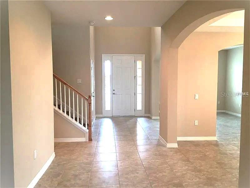 An entryway features tile flooring, a staircase with a wooden railing, and a front door — 4858 TERRA SOLE PLACE, ST CLOUD, FL