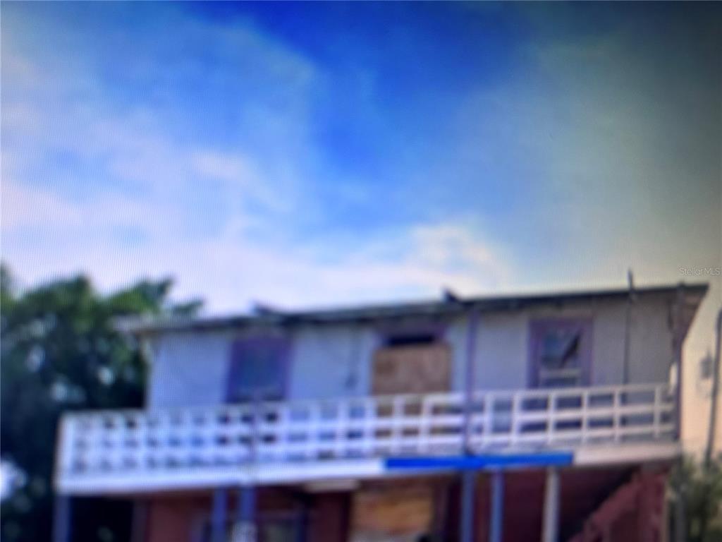 A two-story house with a white balcony railing and boarded-up windows — 624 SW AVENUE C PLACE UNIT 20, BELLE GLADE, FL