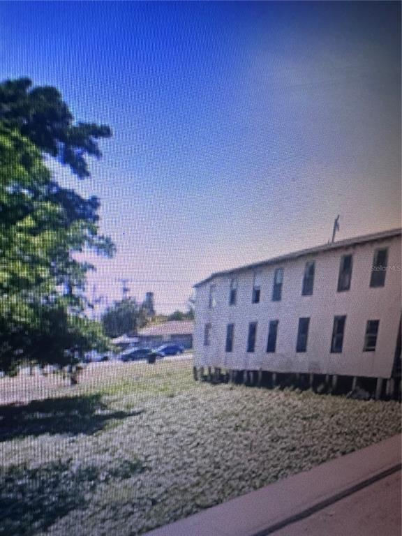 A two-story building with white siding stands on stilts above a grassy lot — 624 SW AVENUE C PLACE UNIT 20, BELLE GLADE, FL
