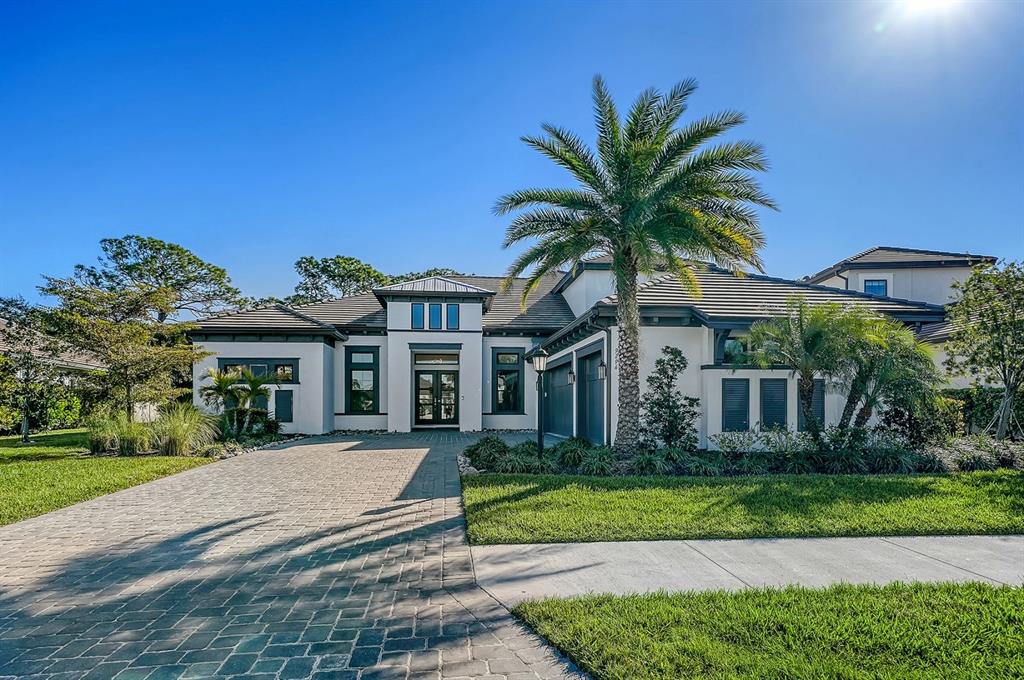 A single-story house with a paver driveway, a palm tree, and a dark-trimmed exterior — 9296 STARRY NIGHT AVENUE, SARASOTA, FL