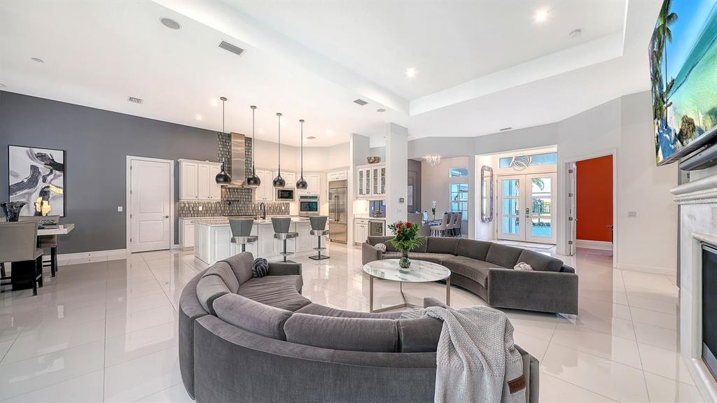 A spacious open-concept living room and kitchen featuring white tile floors and grey furniture — 9296 STARRY NIGHT AVENUE, SARASOTA, FL