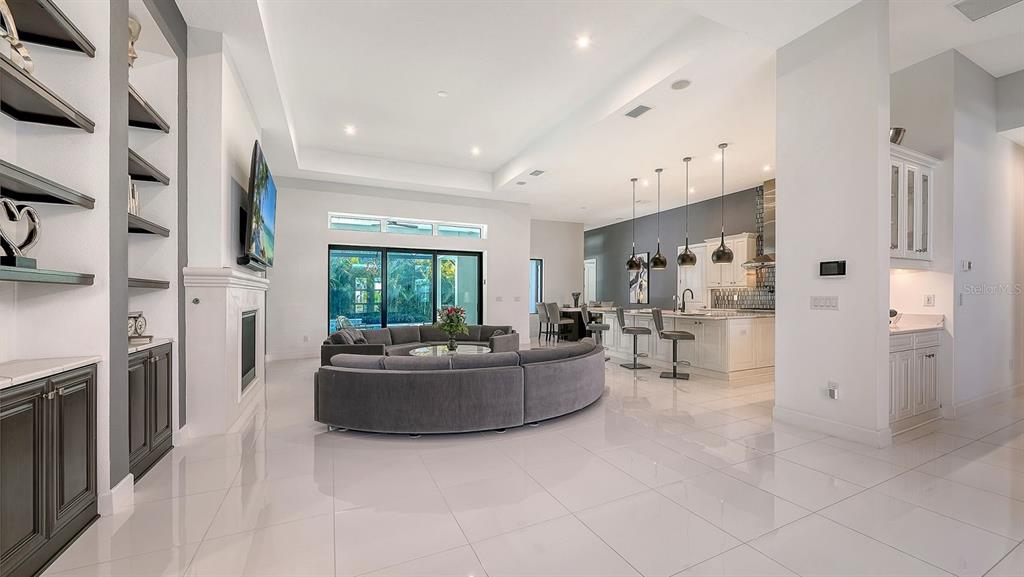 A spacious open-concept living room and kitchen featuring white tile floors and a curved sofa — 9296 STARRY NIGHT AVENUE, SARASOTA, FL