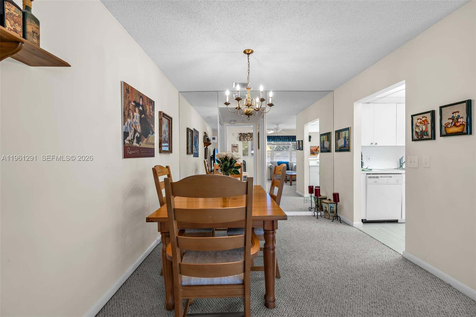 A dining area features a wooden table, chairs, a chandelier, and a mirrored wall — 316 Tilford O # 316, Deerfield Beach FL 33442, DEERFIELD BEACH, FL