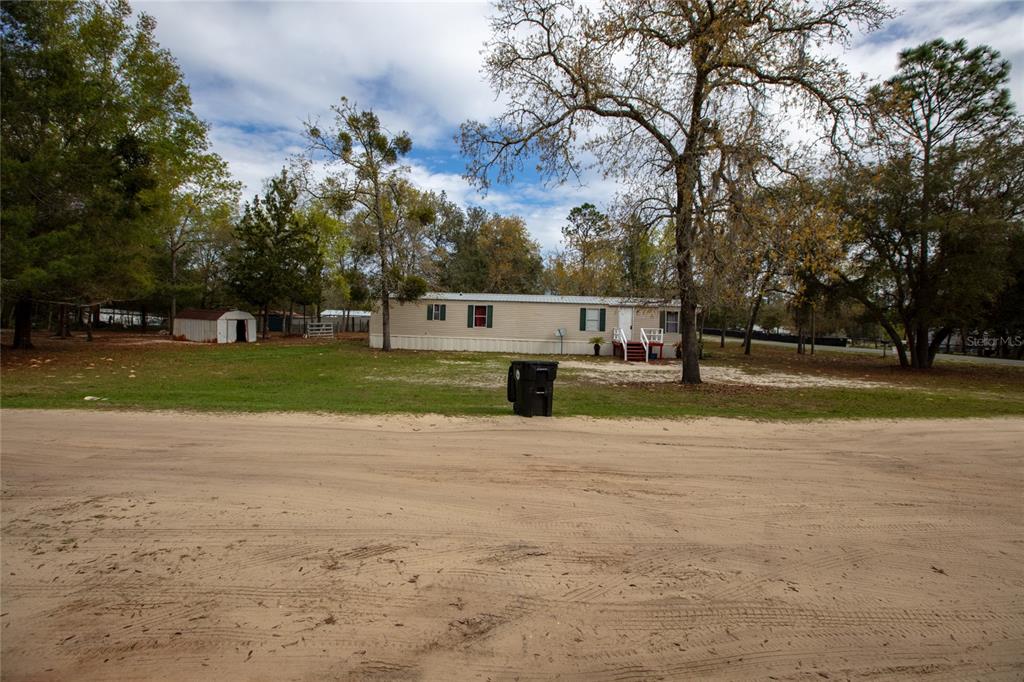 A single-story mobile home sits on a sandy lot surrounded by trees — 7160 PURDUE STREET, KEYSTONE HEIGHTS, FL
