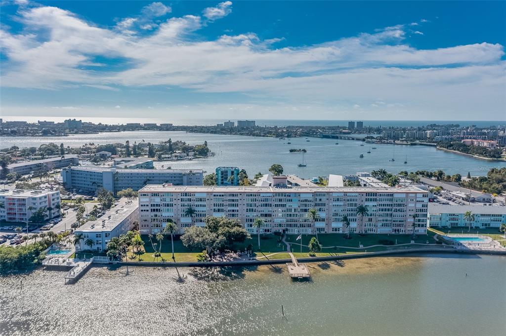 An aerial view shows a multi-story apartment complex situated along a waterfront with a dock — 1847 SHORE DRIVE S UNIT 117, SOUTH PASADENA, FL