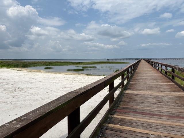 A wooden pier extends over a sandy beach toward a large lake under a cloudy sky — 213 PLUMOSA DRIVE, INDIAN LAKE ESTATES, FL
