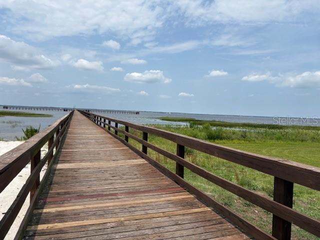 A long wooden boardwalk extends over a grassy area toward a large body of water — 213 PLUMOSA DRIVE, INDIAN LAKE ESTATES, FL
