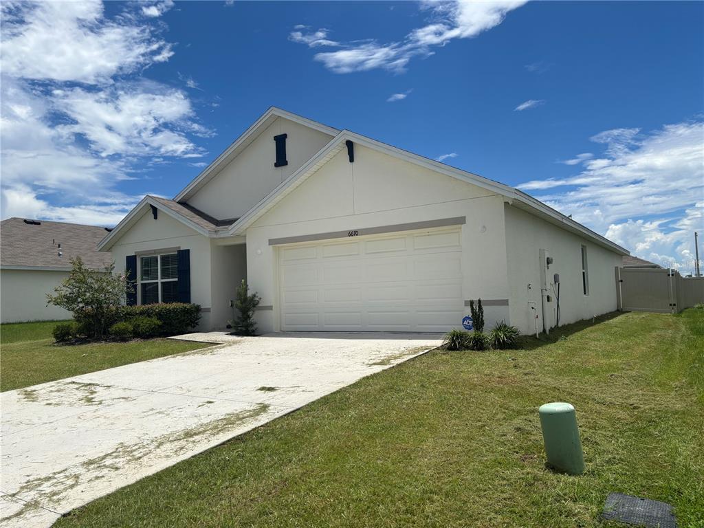 A single-story house with a white stucco exterior, a two-car garage, and a concrete driveway — 6670 SE 3RD LOOP, OCALA, FL