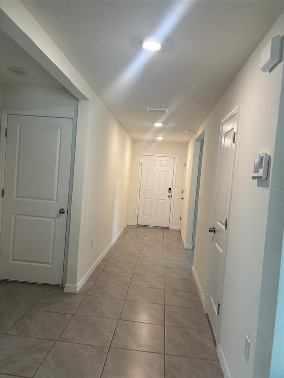 A hallway with light-colored tile flooring leads to a white front door — 6670 SE 3RD LOOP, OCALA, FL