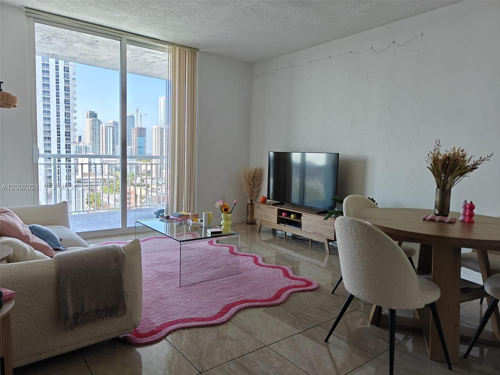 A living and dining area features a pink rug, glass coffee table, and city balcony view — 275 NE 18th St # 1801, Miami FL 33132, MIAMI, FL