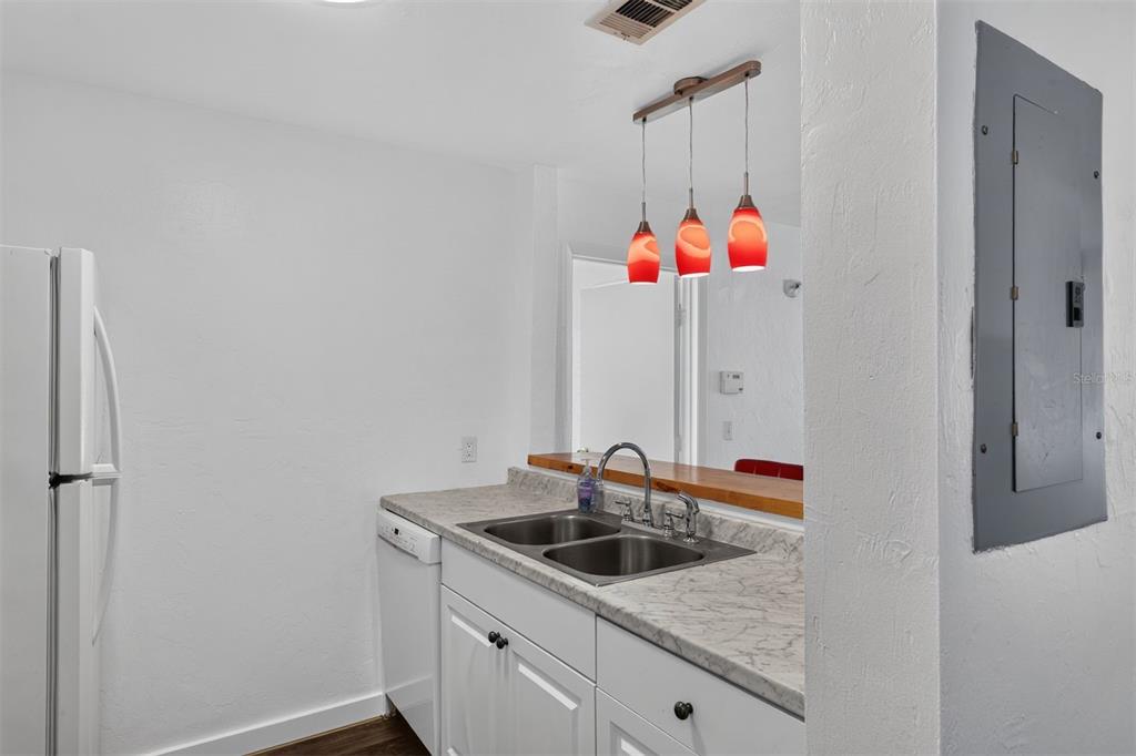 A kitchen features white cabinets, marble-look countertops, a double sink, and three red pendant lights — 4000 SW 23RD STREET UNIT 1-101, GAINESVILLE, FL