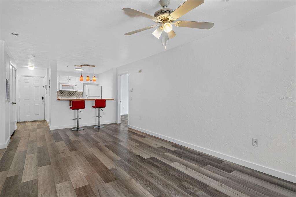 An open-concept living area features wood-look flooring, a ceiling fan, and a kitchen breakfast bar — 4000 SW 23RD STREET UNIT 1-101, GAINESVILLE, FL