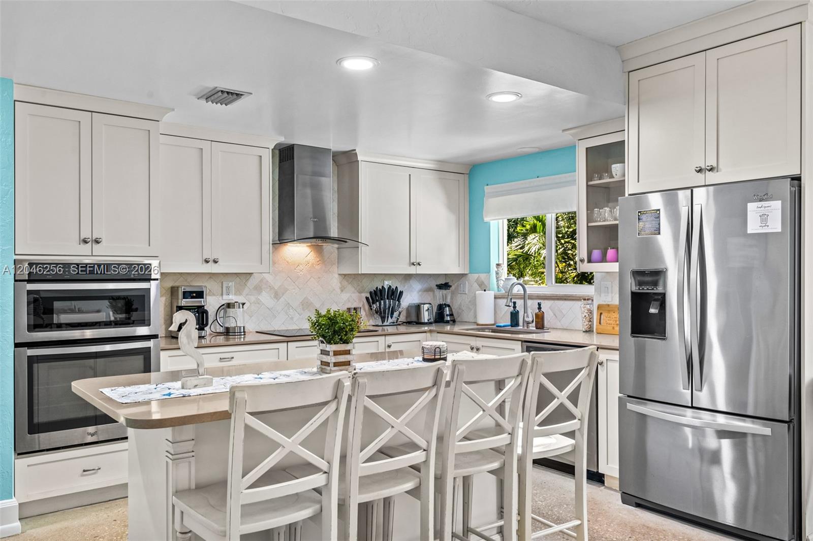 A kitchen features white cabinetry, stainless steel appliances, a center island, and a light backsplash — 517 NE 2nd Pl, Dania Beach FL 33004, DANIA BEACH, FL
