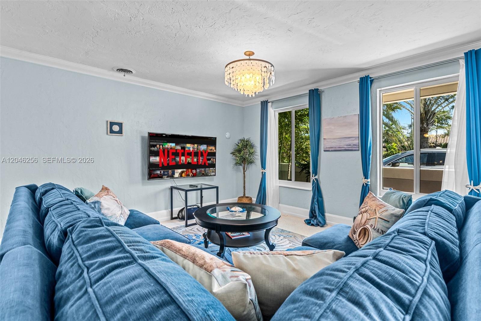 A living room features a blue sectional sofa, a round coffee table, and a wall-mounted television — 517 NE 2nd Pl, Dania Beach FL 33004, DANIA BEACH, FL