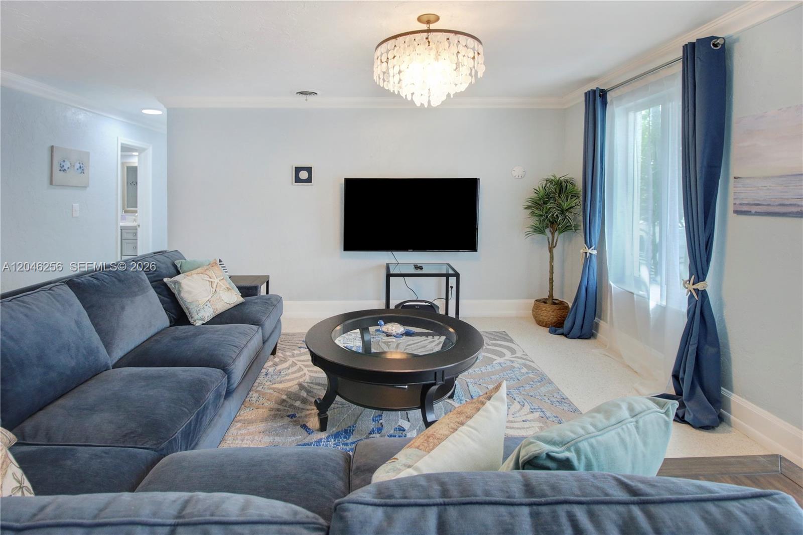 A living room features a blue sectional sofa, a round glass coffee table, and a television — 517 NE 2nd Pl, Dania Beach FL 33004, DANIA BEACH, FL