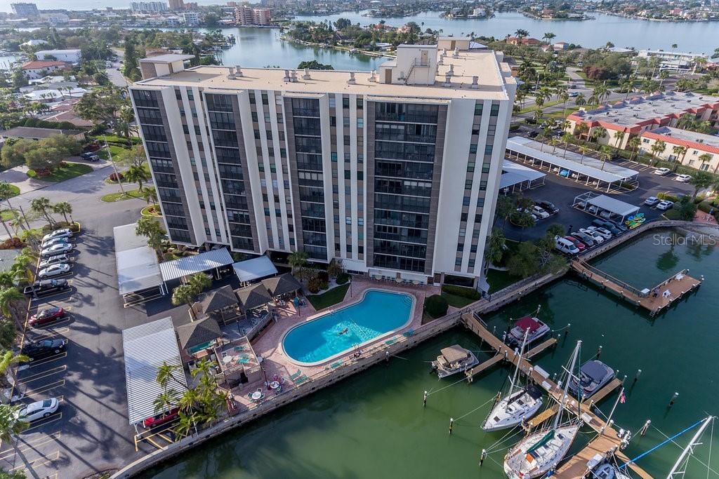 An aerial view of a multi-story apartment building with a pool and boat slips — 10355 PARADISE BOULEVARD UNIT 103, TREASURE ISLAND, FL