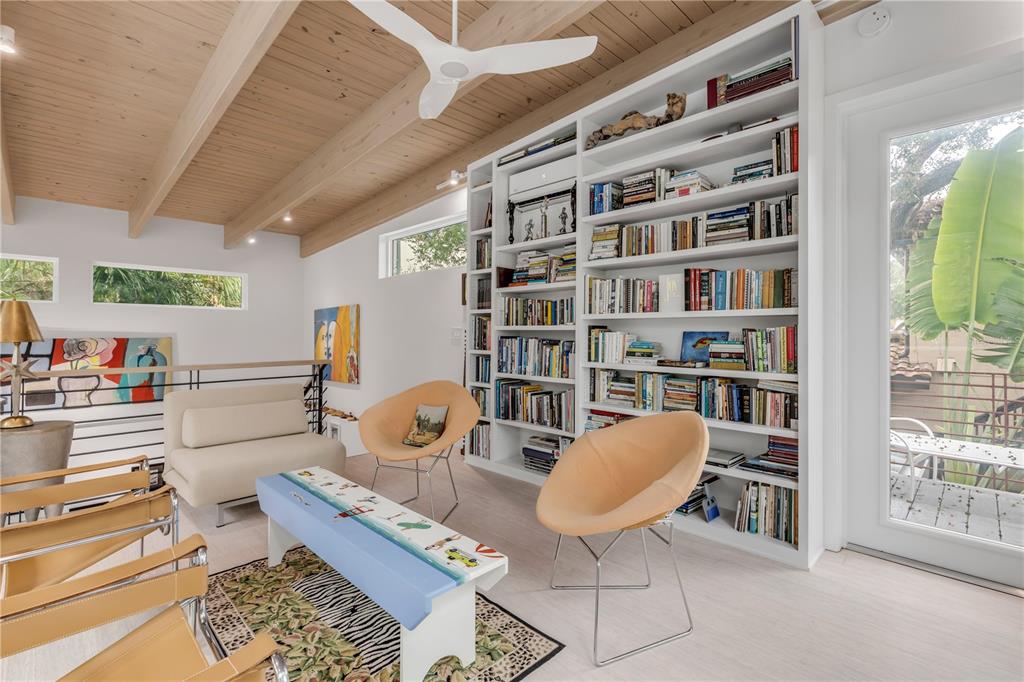 A living room features a large white bookshelf, two tan chairs, and a vaulted ceiling — 210 FLORIDA AVENUE, NEW SMYRNA BEACH, FL
