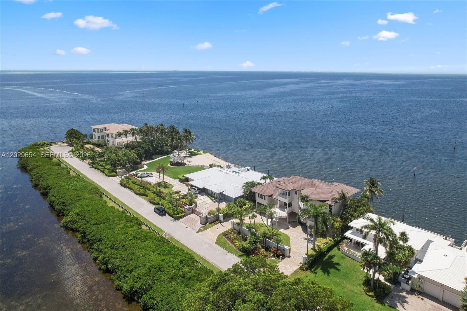 An aerial view shows several waterfront houses situated along a road lined with dense vegetation — 750 Lugo Ave, Coral Gables FL 33156, CORAL GABLES, FL