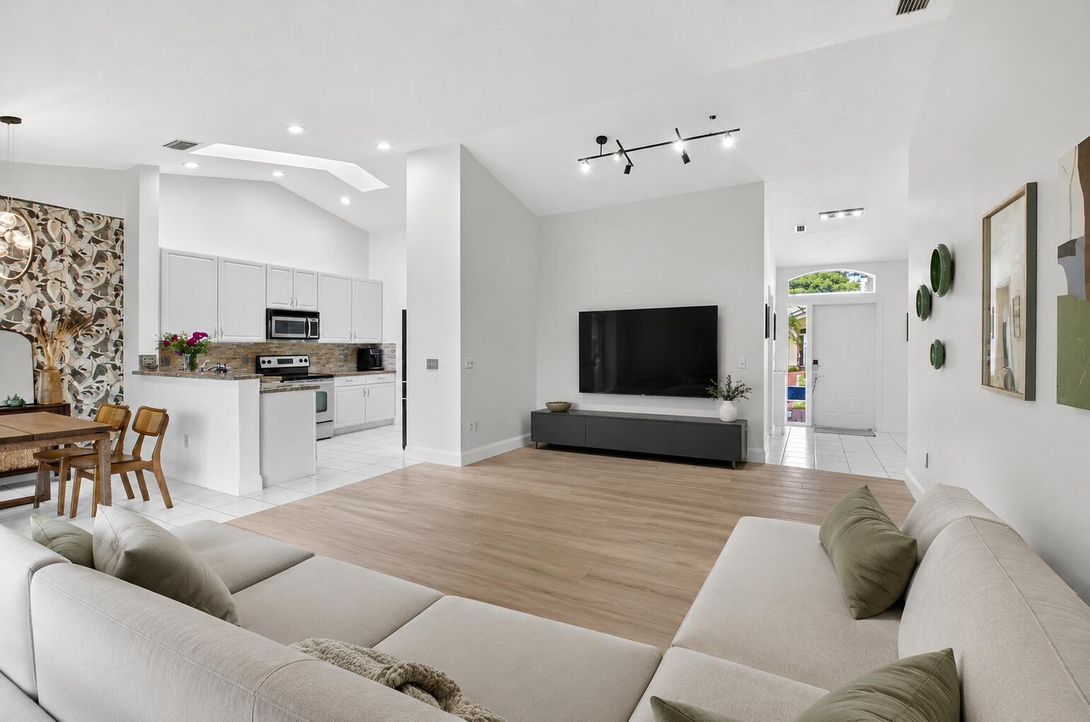 A living room with light wood floors, a large sectional sofa, and an open kitchen — 17257 Boca Club Boulevard Apt 5, Boca Raton FL 33487, BOCA RATON, FL