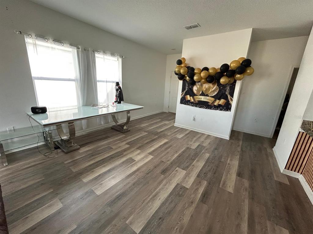 A dining area features wood-look flooring, a glass-topped table, and a black and gold birthday banner — 805 ORCHID GROVE BOULEVARD, DAVENPORT, FL