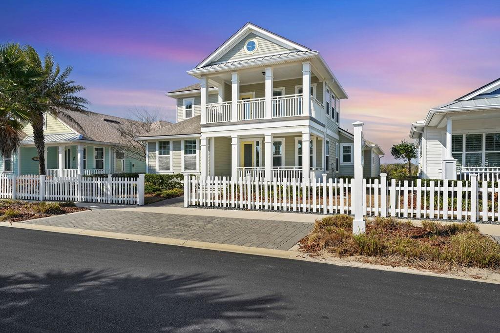 A two-story house with a white picket fence and a paved driveway under a sunset sky — 4 HIDDEN TREASURE DRIVE, PALM COAST, FL