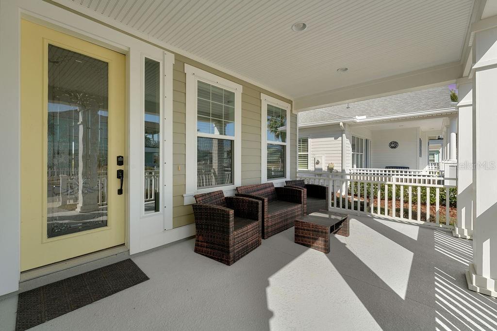 A covered front porch features a yellow door, wicker furniture, and a white railing — 4 HIDDEN TREASURE DRIVE, PALM COAST, FL