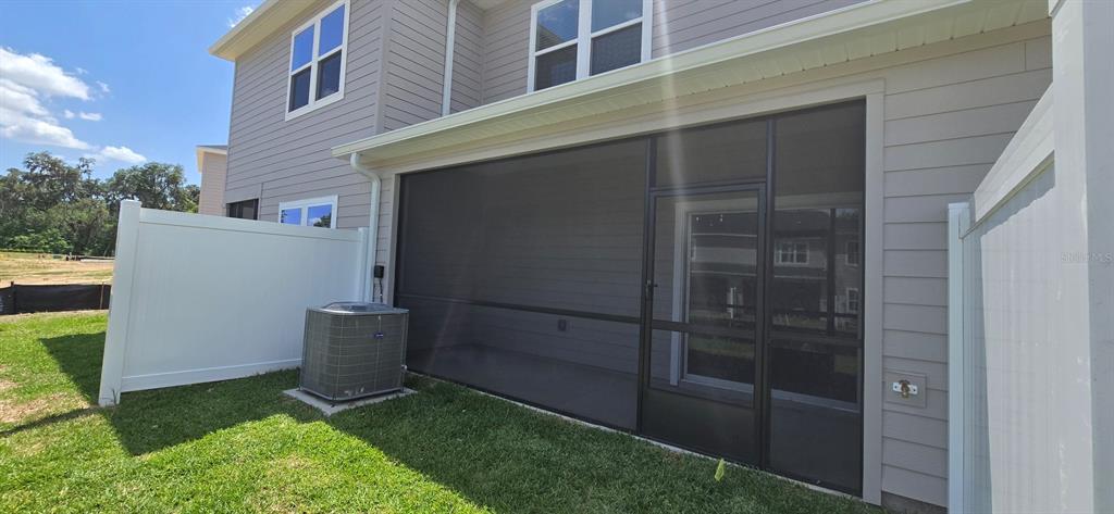 A screened-in patio sits beside an air conditioning unit and a white vinyl privacy fence — 3577 SE 37 COURT, OCALA, FL