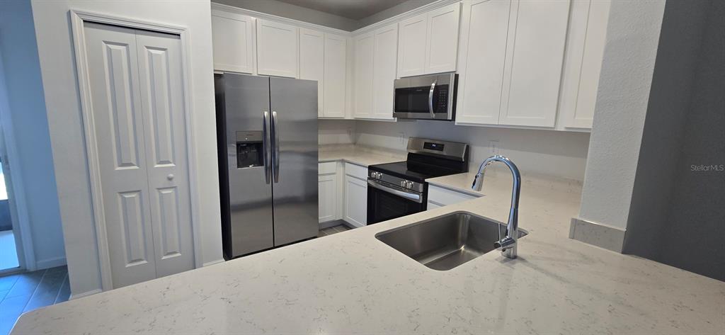 A kitchen features white cabinets, stainless steel appliances, and a light-colored countertop with a sink — 3577 SE 37 COURT, OCALA, FL