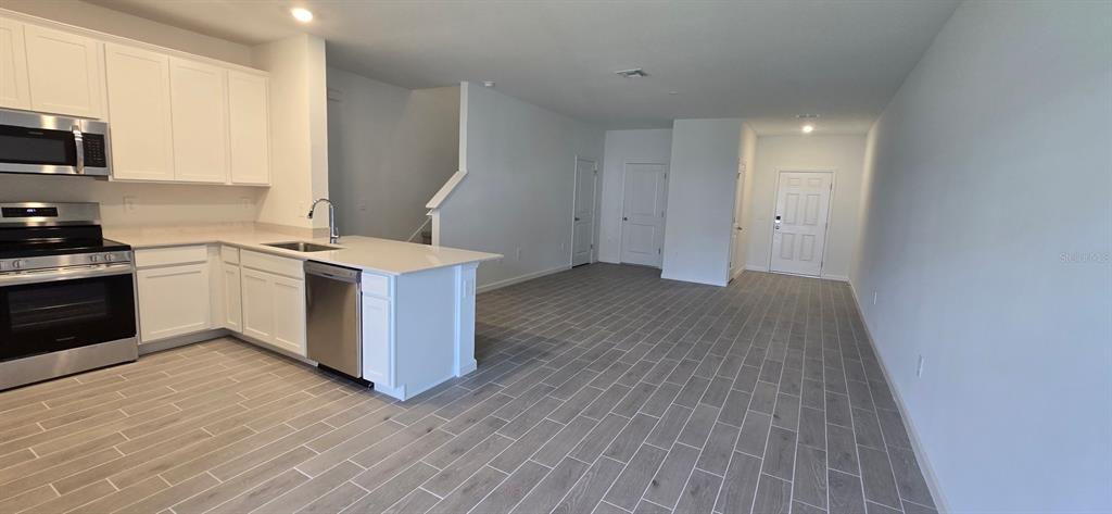 A kitchen with white cabinets and stainless steel appliances opens to a spacious living area — 3577 SE 37 COURT, OCALA, FL