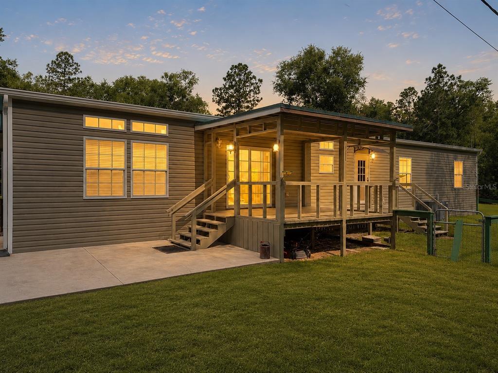 A single-story house with gray siding, a wooden porch, and a concrete patio at dusk — 11160 NW 5TH AVENUE, BRANFORD, FL