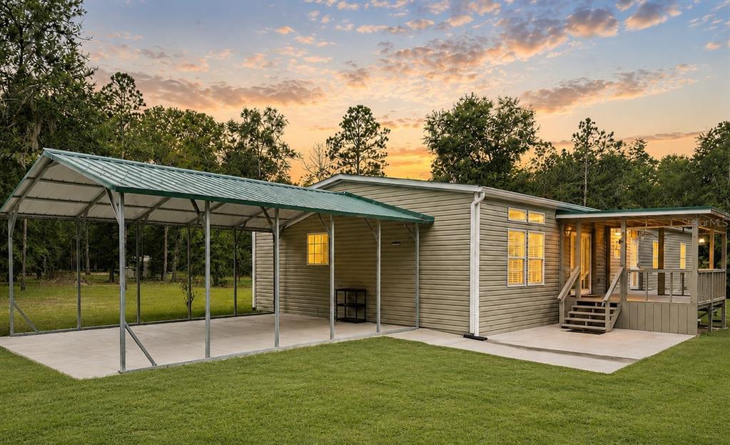A manufactured home with a metal carport and a wooden deck at sunset — 11160 NW 5TH AVENUE, BRANFORD, FL
