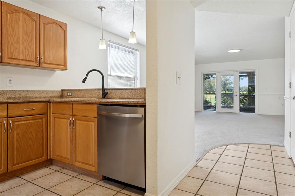 A kitchen with wood cabinets and stainless steel appliances overlooks a carpeted living area — 14902 PAR CLUB CIRCLE, TAMPA, FL
