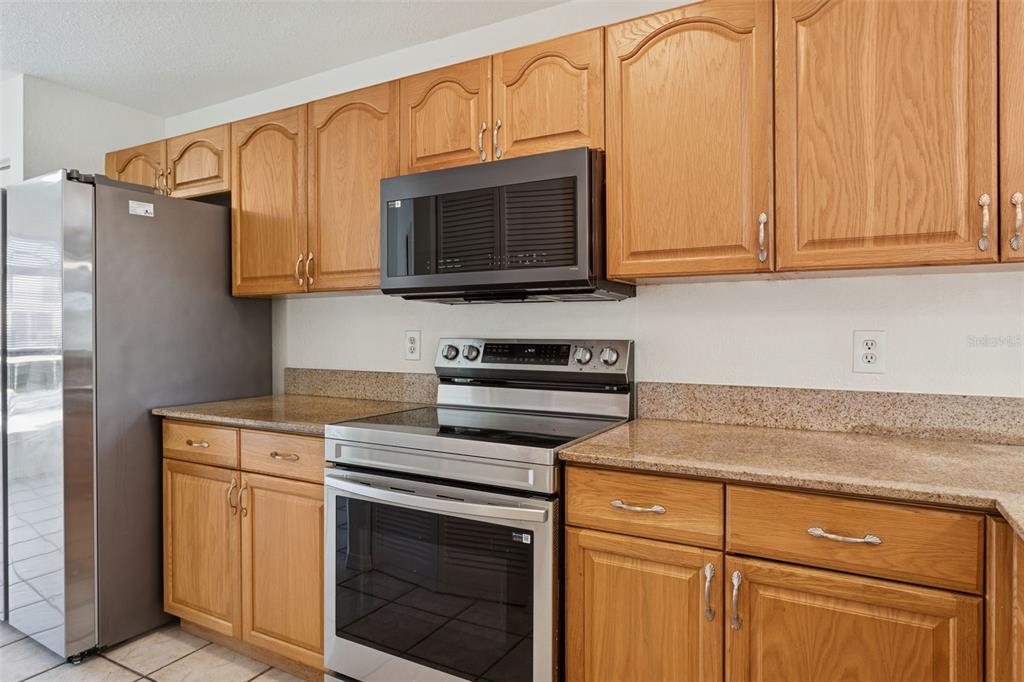 A kitchen featuring oak cabinets, stainless steel appliances, and speckled granite countertops — 14902 PAR CLUB CIRCLE, TAMPA, FL